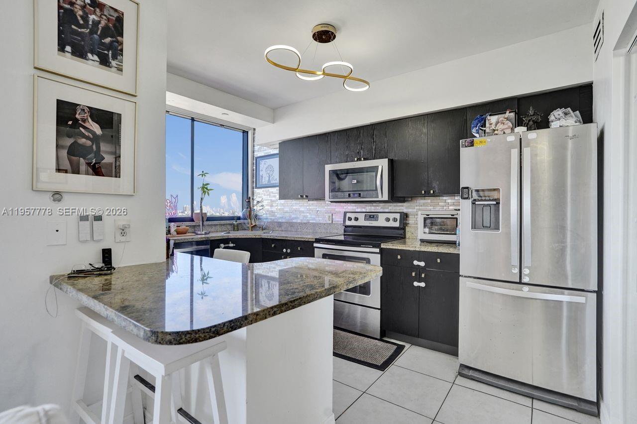 A kitchen features dark cabinets, granite countertops, stainless steel appliances, and a breakfast bar — 1330 West Ave # 1811, Miami Beach FL 33139, MIAMI BEACH, FL