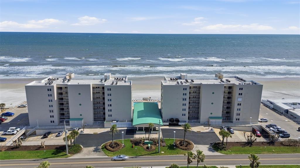 An aerial view of a multi-story beachfront condominium complex with a parking lot and pool — 4495 S ATLANTIC AVENUE UNIT 501, PORT ORANGE, FL