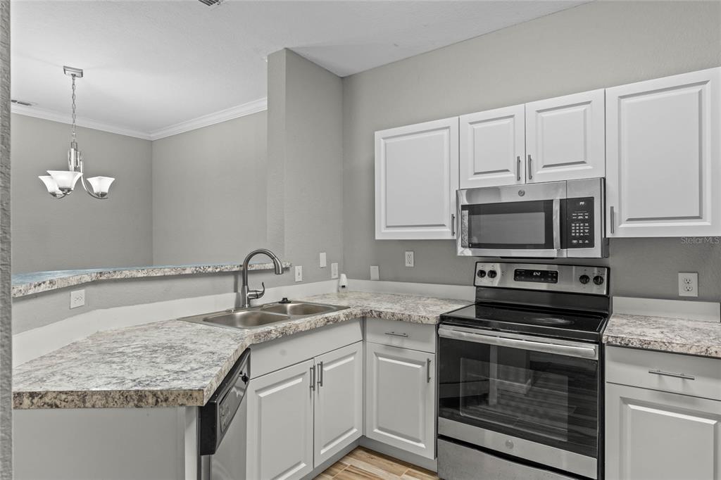 A kitchen with white cabinets, stainless steel appliances, and a granite-look countertop — 5501 PGA BOULEVARD UNIT 4724, ORLANDO, FL