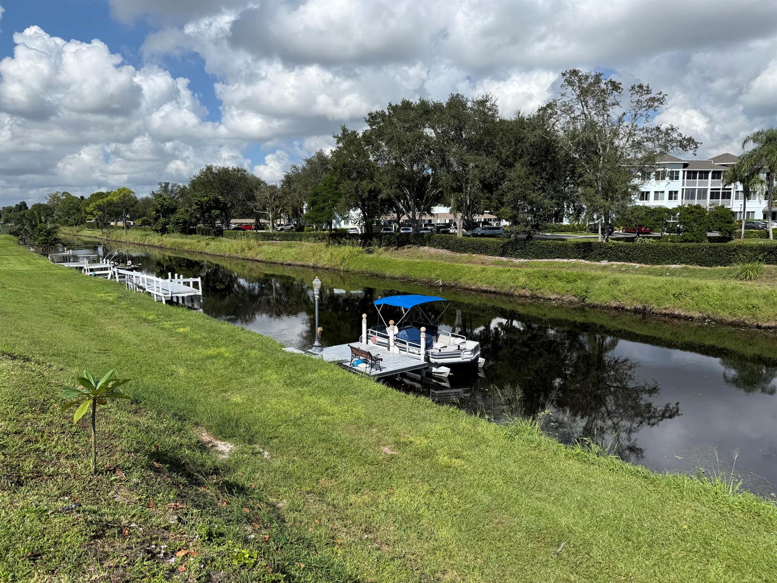 A pontoon boat is docked in a canal alongside a grassy lawn and several piers — 2623 Northside Drive, Lake Worth FL 33462, LAKE WORTH, FL