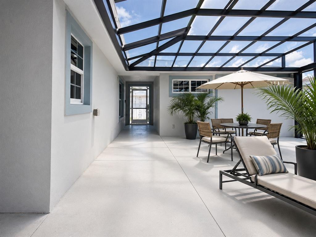 A covered patio features a glass roof, concrete flooring, outdoor furniture, and a potted palm — 17736 SE 115TH COURT, SUMMERFIELD, FL