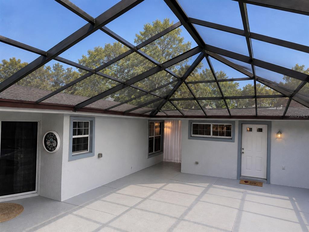 A covered patio with a screened roof, concrete flooring, and white exterior walls — 17736 SE 115TH COURT, SUMMERFIELD, FL