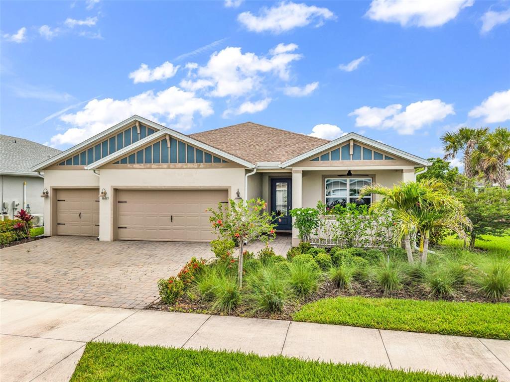 A single-story suburban house with a tan stucco exterior, two-car garage, and landscaped front yard — 16121 LOTUS WAY, PUNTA GORDA, FL