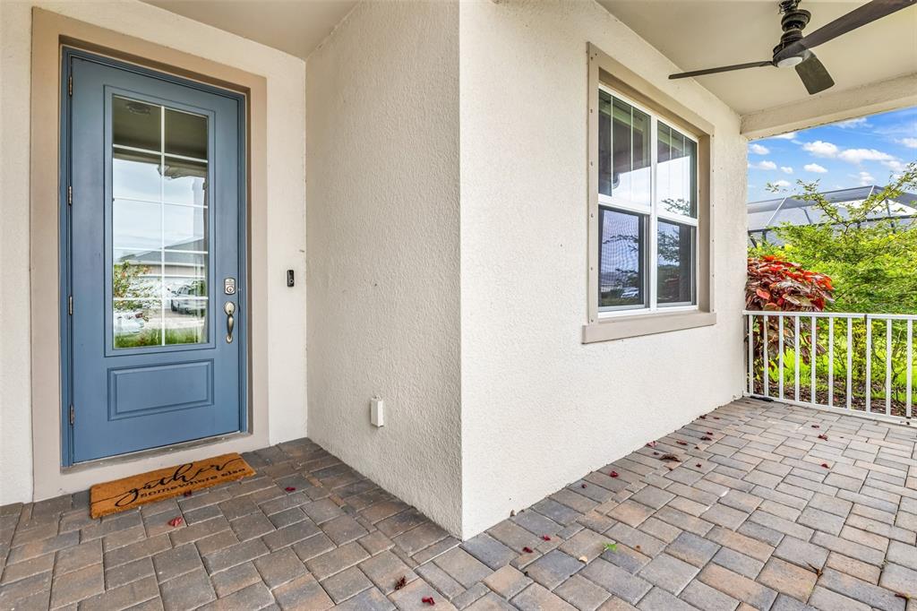 A blue front door with a glass panel opens onto a paved porch with a window — 16121 LOTUS WAY, PUNTA GORDA, FL