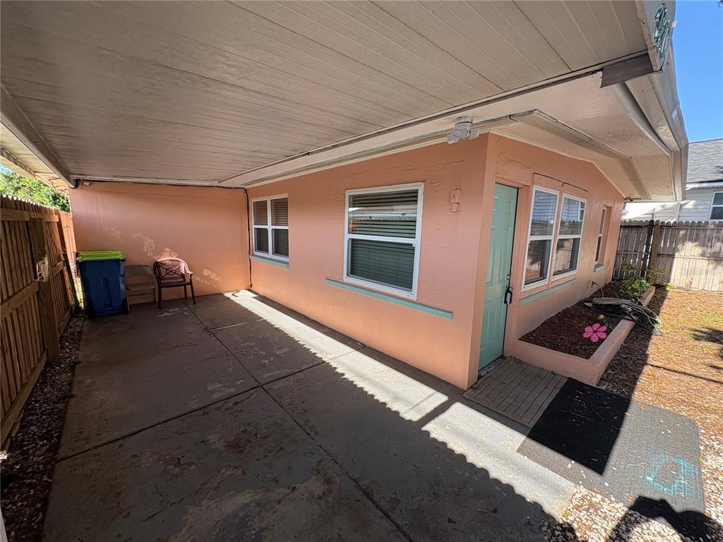 A peach-colored house exterior features a covered concrete patio, a light green door, and windows — 4920 45TH AVENUE N, ST PETERSBURG, FL