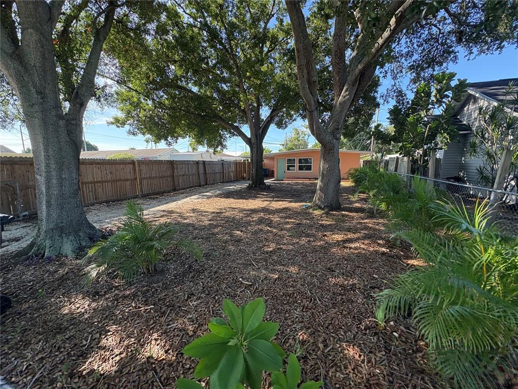 A large backyard features mature trees, wood mulch ground cover, and a wooden privacy fence — 4920 45TH AVENUE N, ST PETERSBURG, FL