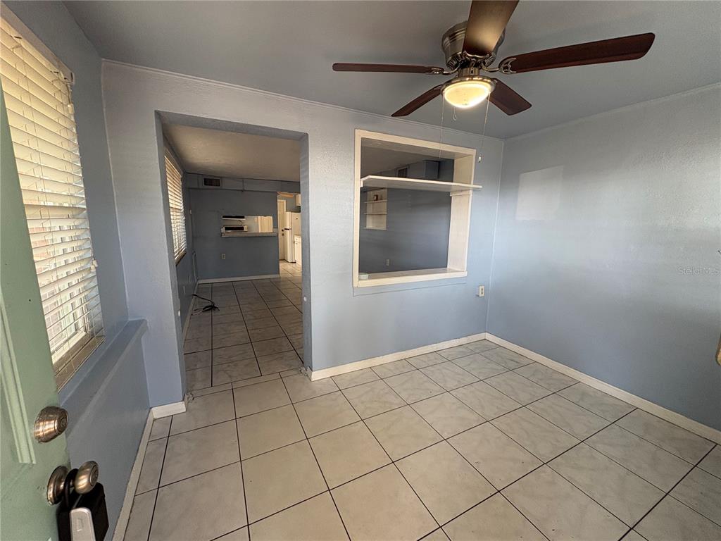 A light blue room with tile flooring, a ceiling fan, and a pass-through window opening — 4920 45TH AVENUE N, ST PETERSBURG, FL