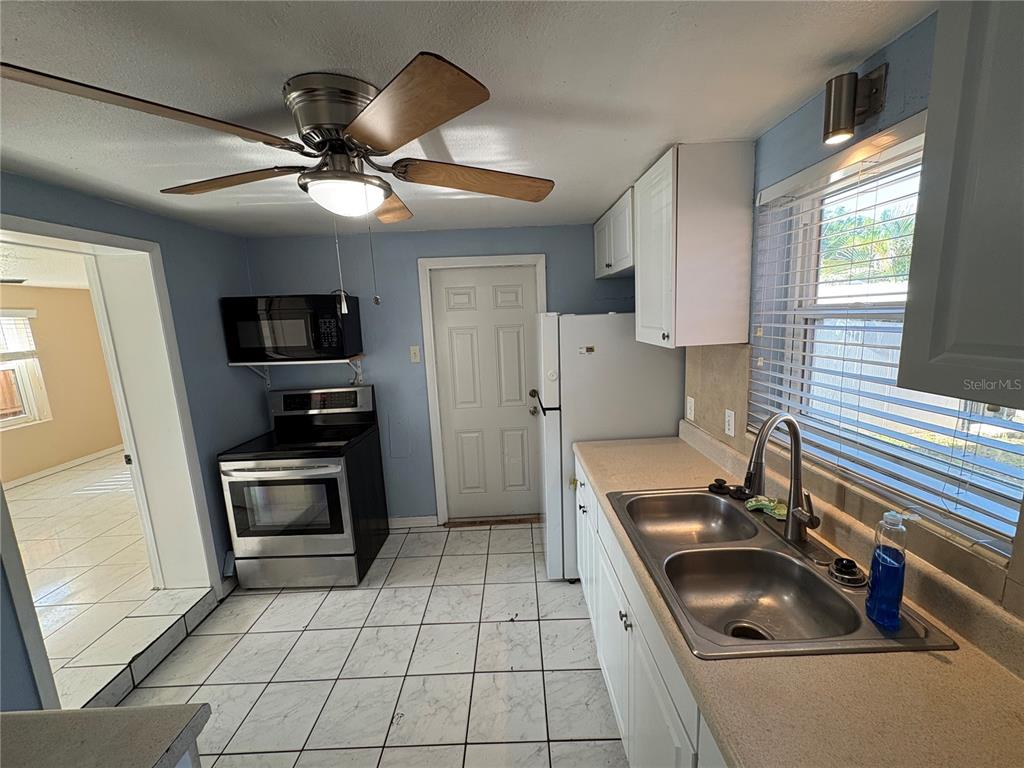 A kitchen with white cabinets, stainless steel appliances, a double sink, and tiled flooring — 4920 45TH AVENUE N, ST PETERSBURG, FL