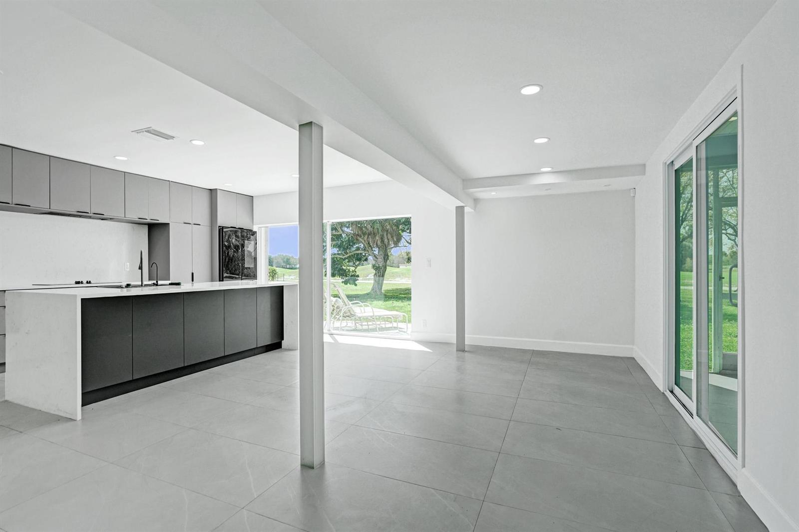 A modern kitchen with a large island, gray cabinetry, and sliding glass doors to outdoors — 6700 E Tropical Way, Plantation FL 33317, PLANTATION, FL