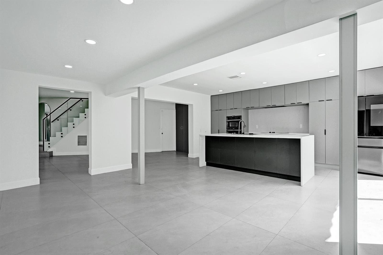 A modern kitchen features a dark island, gray cabinetry, and light tile flooring — 6700 E Tropical Way, Plantation FL 33317, PLANTATION, FL