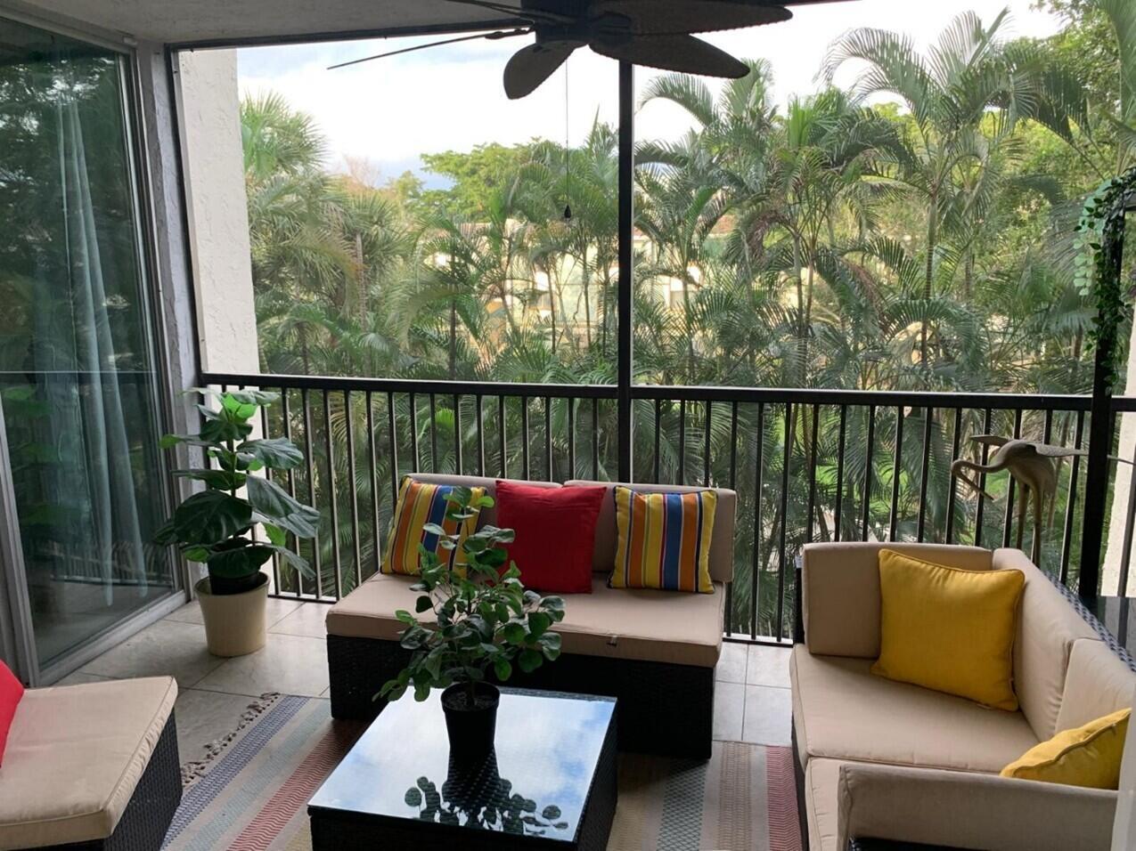 A screened-in balcony features outdoor furniture, potted plants, and a view of palm trees — 3940 Inverrary Boulevard # 302, Lauderhill FL 33319, LAUDERHILL, FL