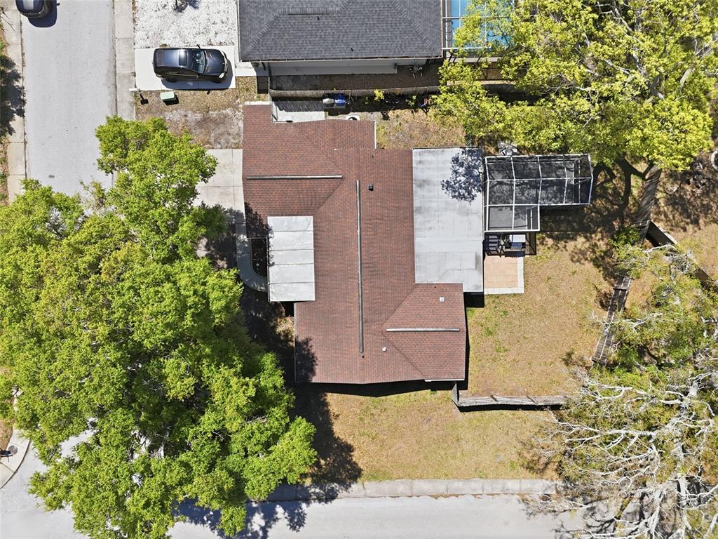 An aerial view shows a house with a brown shingled roof and a screened-in patio — 9825 LAKESIDE LANE, PORT RICHEY, FL