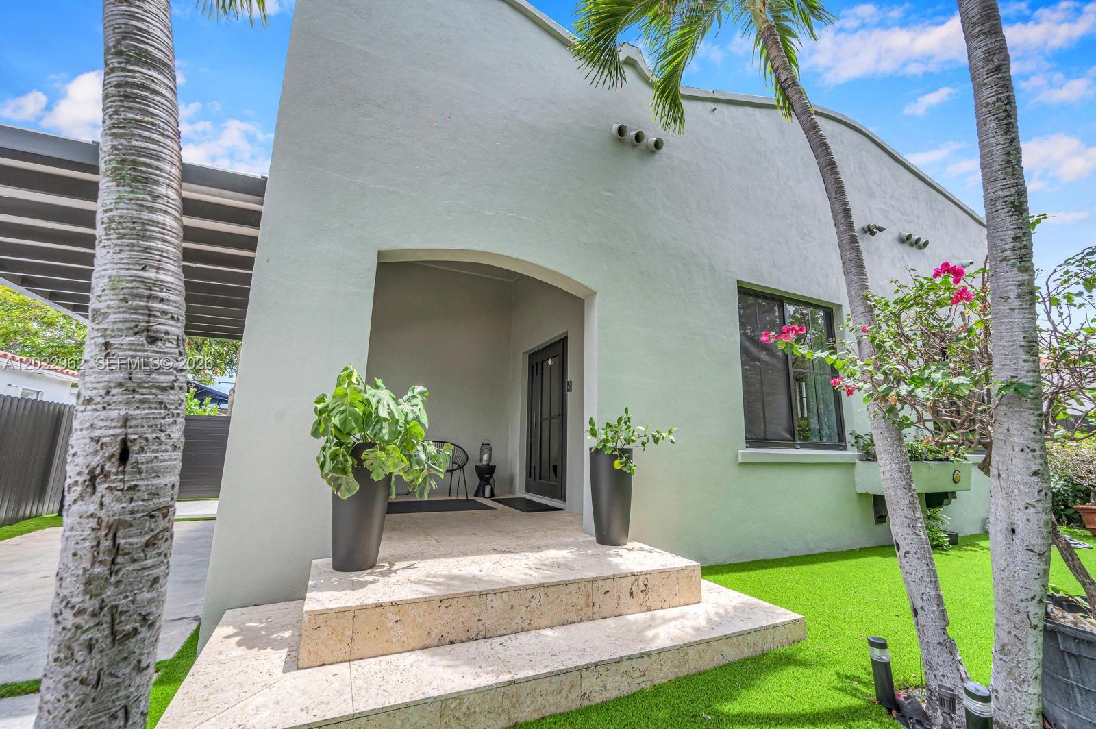 The exterior of a light-colored house features a covered entryway with stone steps and planters — 1852 SW 10th St, Miami FL 33135, MIAMI, FL