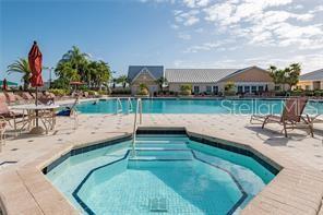 A hot tub sits in the foreground of a community pool area with lounge chairs — 1867 NOTTINGHAM TRAIL, PORT CHARLOTTE, FL