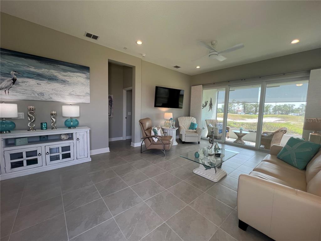 A living room features tile flooring, a white media console, and sliding glass doors — 1867 NOTTINGHAM TRAIL, PORT CHARLOTTE, FL