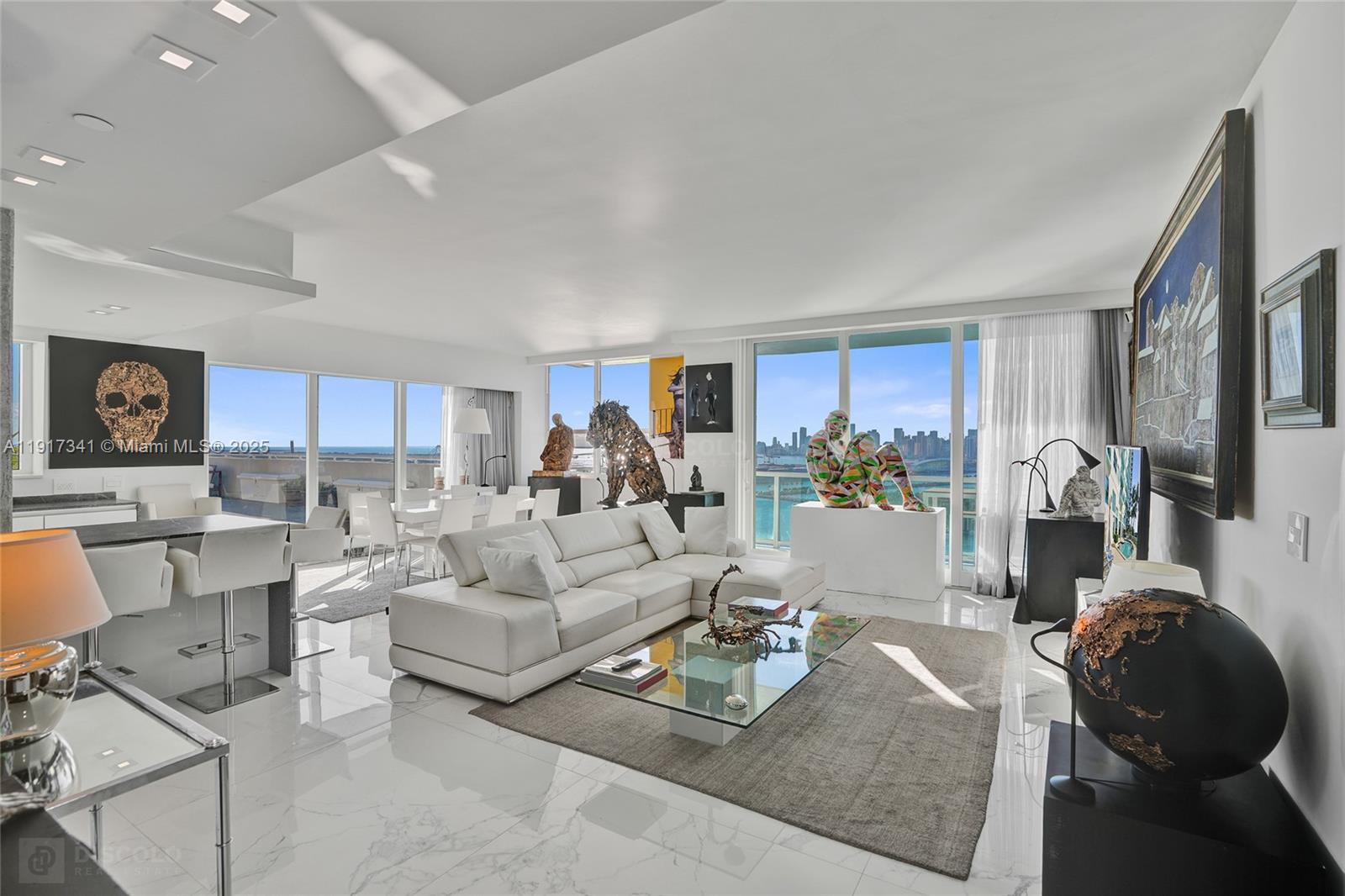 A modern living room features white marble floors, a white sectional sofa, and floor-to-ceiling windows — 650 West Ave, Miami Beach FL 33139, MIAMI BEACH, FL