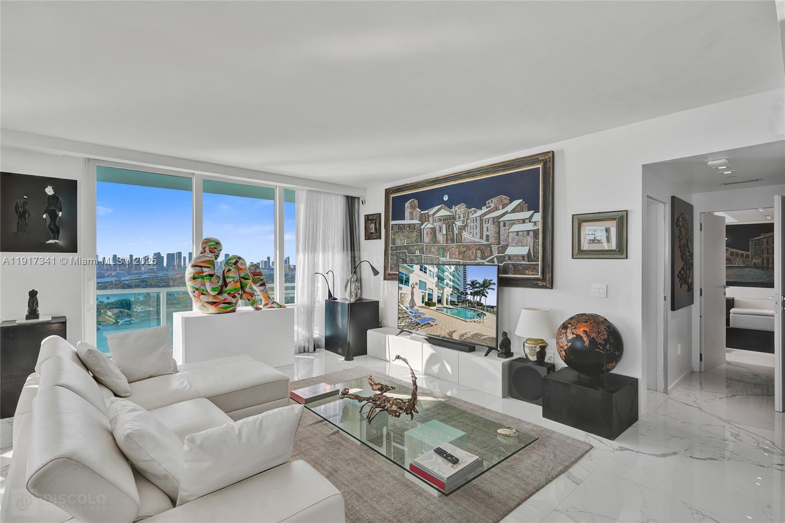 A modern living room features white marble floors, a white sectional sofa, and city views — 650 West Ave, Miami Beach FL 33139, MIAMI BEACH, FL