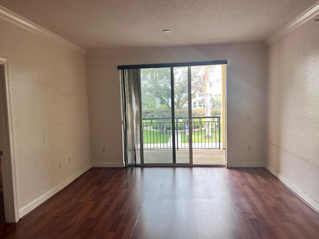 An empty living room features dark wood-look flooring, beige walls, and a sliding glass door — 3 Renaissance Way # 204, Boynton Beach FL 33426, BOYNTON BEACH, FL