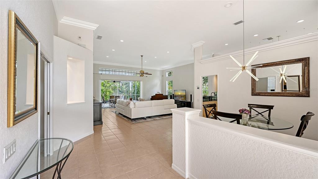 An open-concept living and dining area features tile flooring, a white sectional, and modern lighting — 7318 WINDEMERE LANE, UNIVERSITY PARK, FL