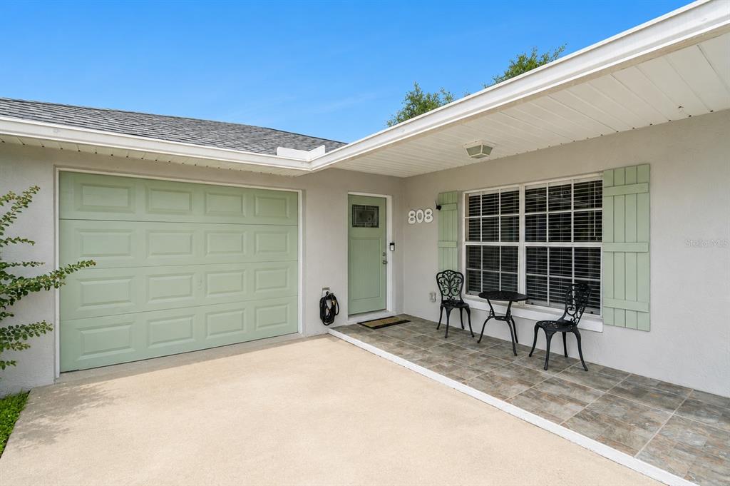 The exterior of a house features a light green garage door, front door, and shutters — 808 ORANGE BROOK DRIVE, MINNEOLA, FL