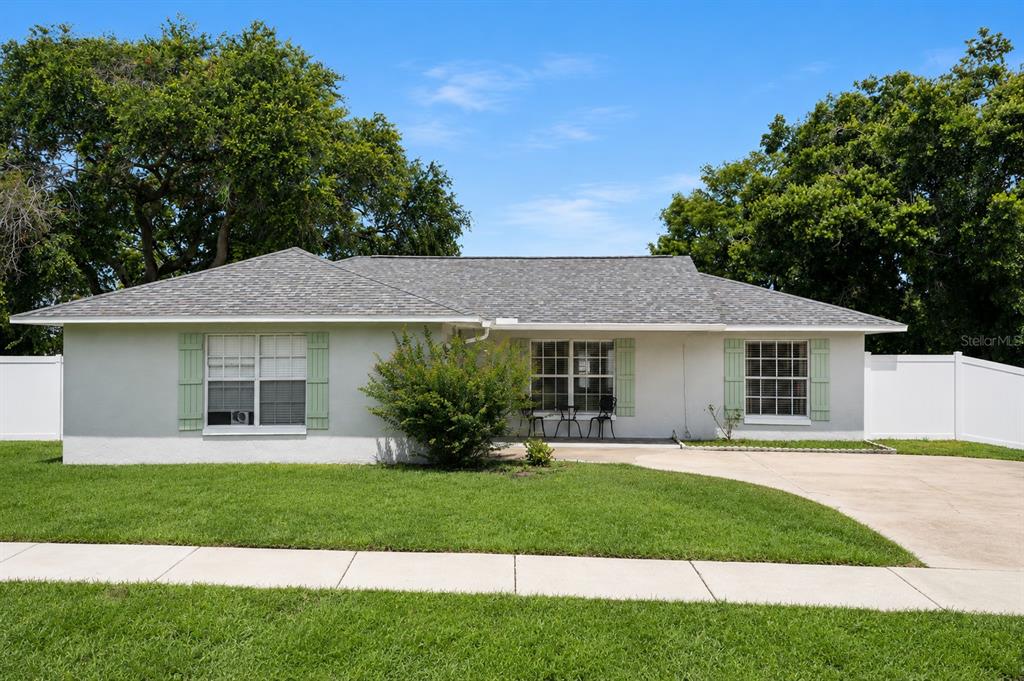 A single-story house with a light-colored exterior, green shutters, and a concrete driveway — 808 ORANGE BROOK DRIVE, MINNEOLA, FL