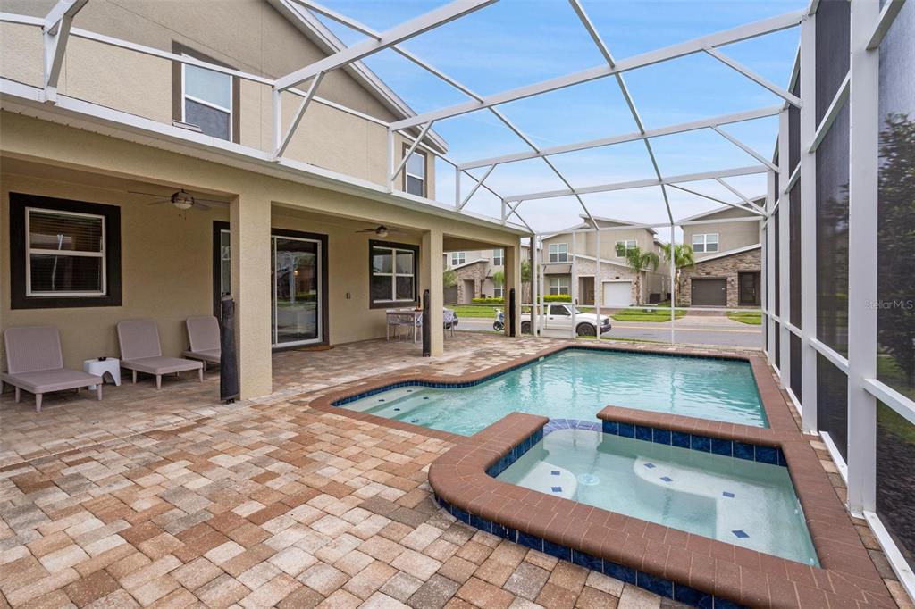 A screened-in patio features a paver deck, a swimming pool, and an attached hot tub — 870 DROP SHOT DRIVE, DAVENPORT, FL