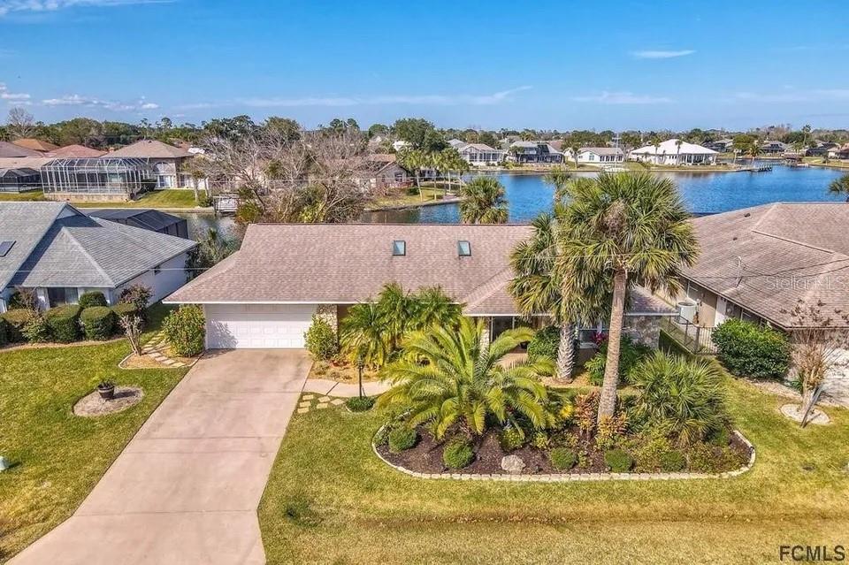An aerial view of a single-story house with a driveway, landscaping, and a waterfront backyard — 13 CEDARFORD COURT, PALM COAST, FL