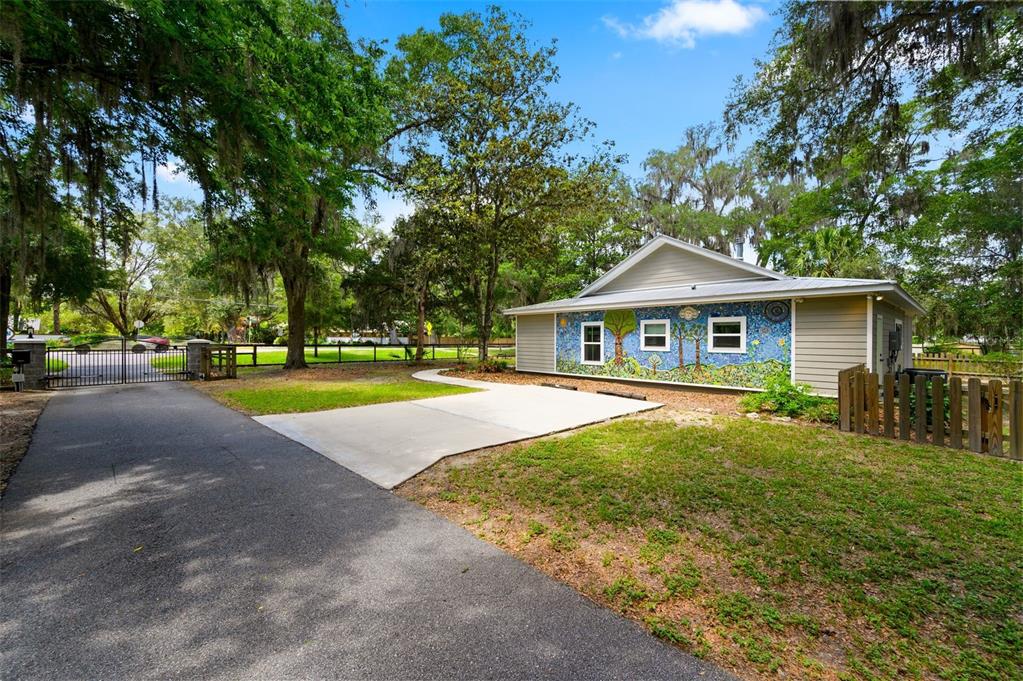 A single-story house with a colorful mural on its side wall sits near a driveway — 2620 NW 31ST AVENUE, GAINESVILLE, FL