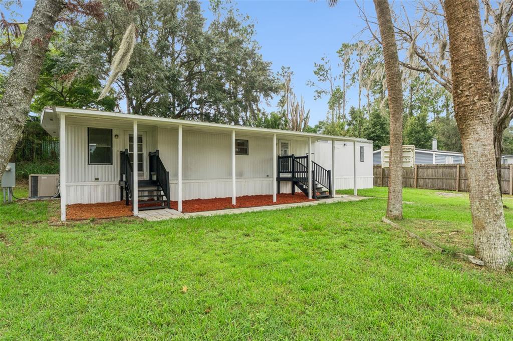 A white mobile home with a covered porch and black stairs sits on a grassy lot — 16842 ELDERBERRY DRIVE, MONTVERDE, FL