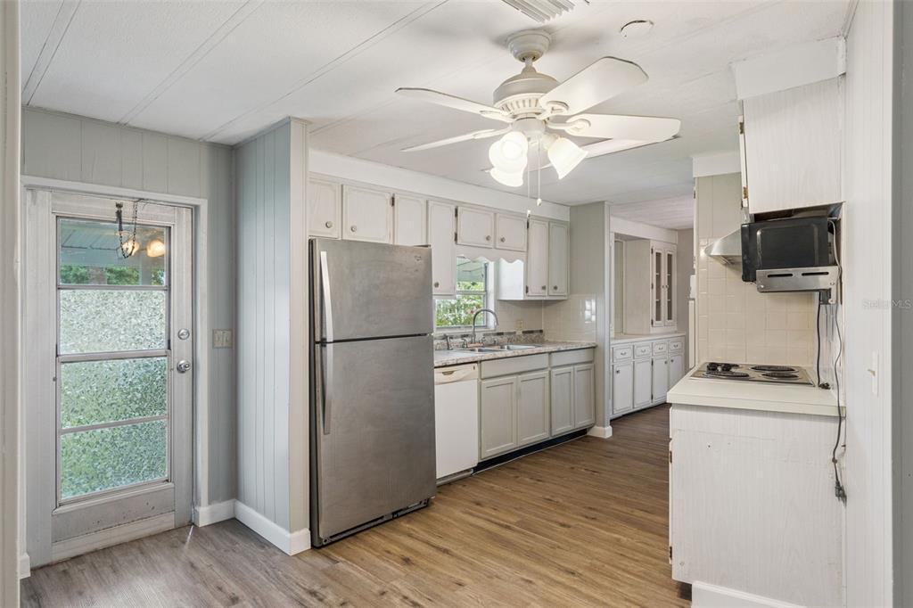 A kitchen with light-colored cabinets, stainless steel refrigerator, wood-look flooring, and a ceiling fan — 16842 ELDERBERRY DRIVE, MONTVERDE, FL