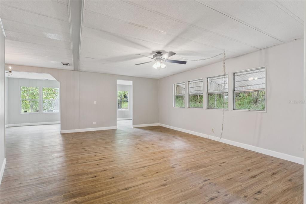 A spacious living room with light gray walls, wood-look flooring, and a ceiling fan — 16842 ELDERBERRY DRIVE, MONTVERDE, FL