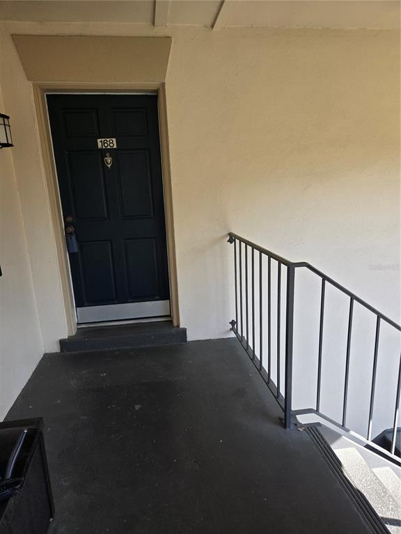 A dark blue front door with the number 168 sits at the top of outdoor stairs — 10342 CARROLLWOOD LANE UNIT 168, TAMPA, FL