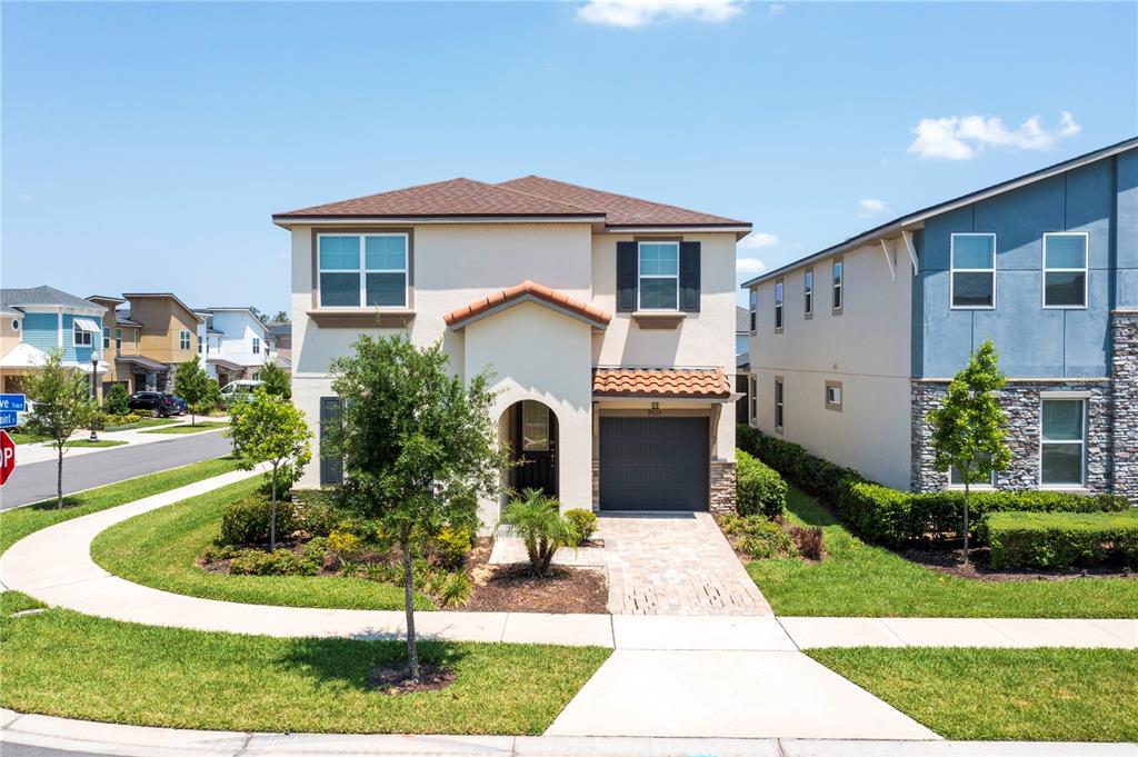 A two-story house with a beige stucco exterior, a tiled roof, and a single-car garage — 9039 PELICAN COVE TRACE, KISSIMMEE, FL