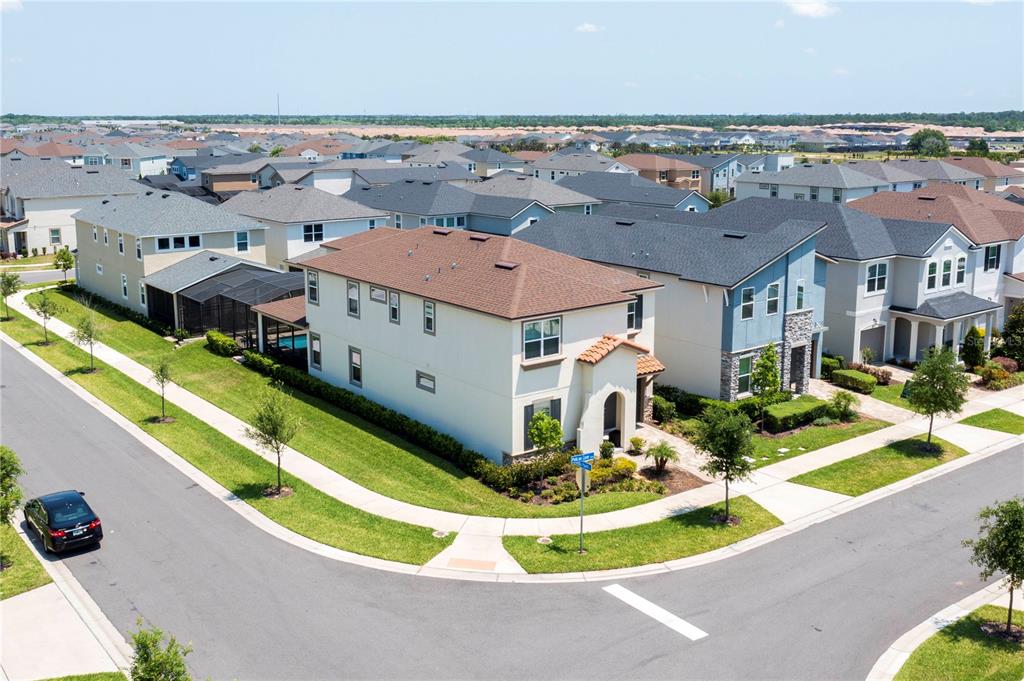 An aerial view of a two-story suburban house on a corner lot with a pool — 9039 PELICAN COVE TRACE, KISSIMMEE, FL