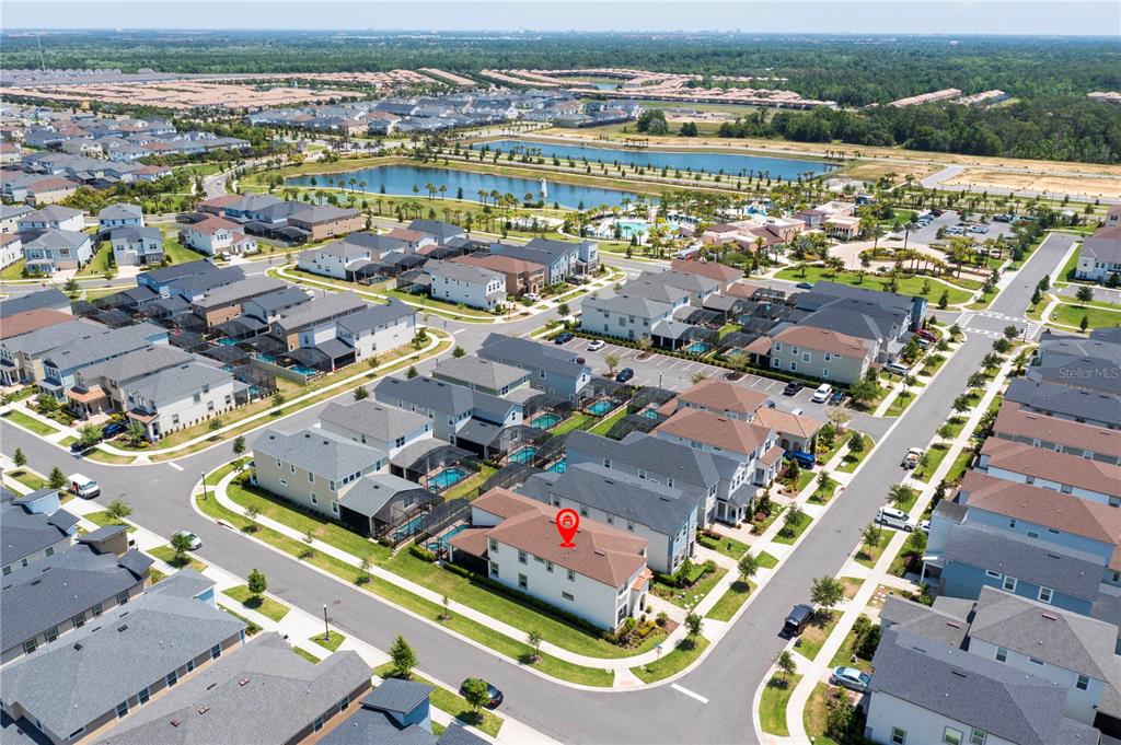 An aerial view shows a suburban neighborhood with a marked house and a nearby lake — 9039 PELICAN COVE TRACE, KISSIMMEE, FL