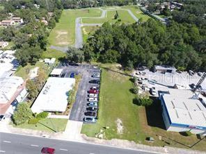 An aerial view shows a commercial building with a parking lot next to a vacant lot — E. NORTH BLVD (US HWY 441), LEESBURG, FL
