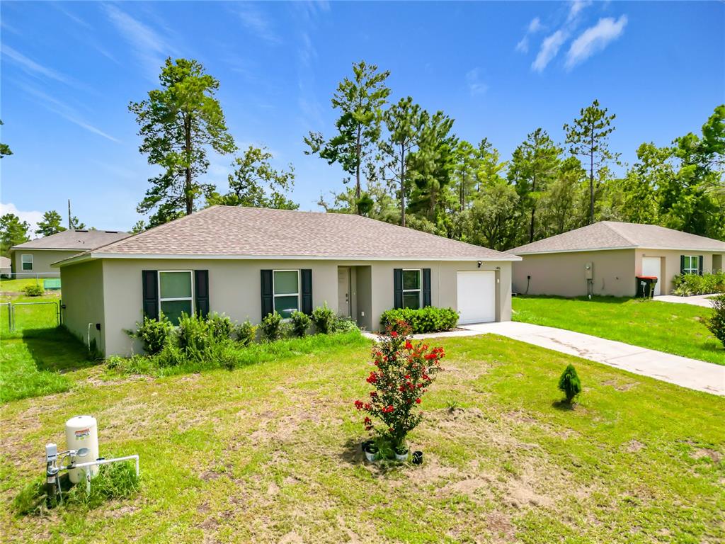 A single-story house with a light-colored exterior, black shutters, and a white garage door — 5496 SW 153RD STREET ROAD, OCALA, FL