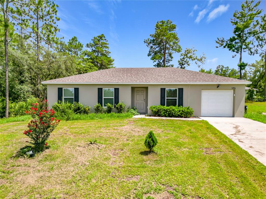A single-story house with a beige exterior, dark shutters, and an attached garage — 5496 SW 153RD STREET ROAD, OCALA, FL
