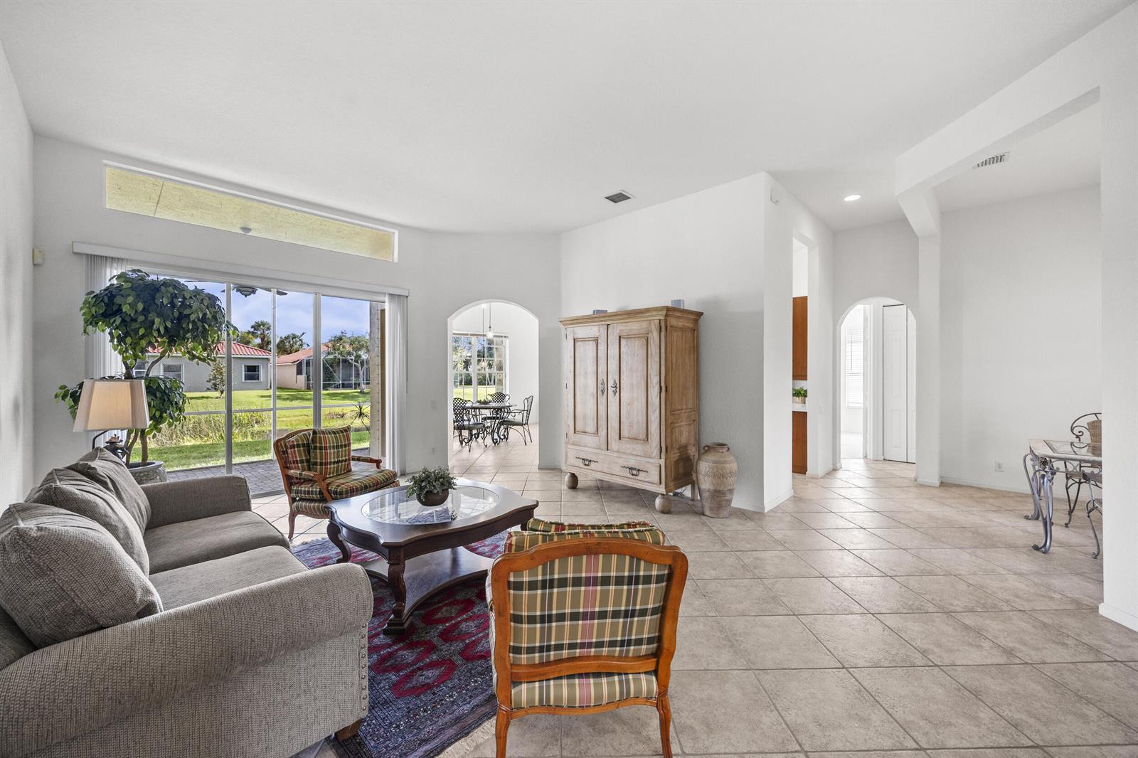 A living room with tile floors, a large wooden armoire, and a view of a backyard — 6721 Arno Way, Boynton Beach FL 33472, BOYNTON BEACH, FL