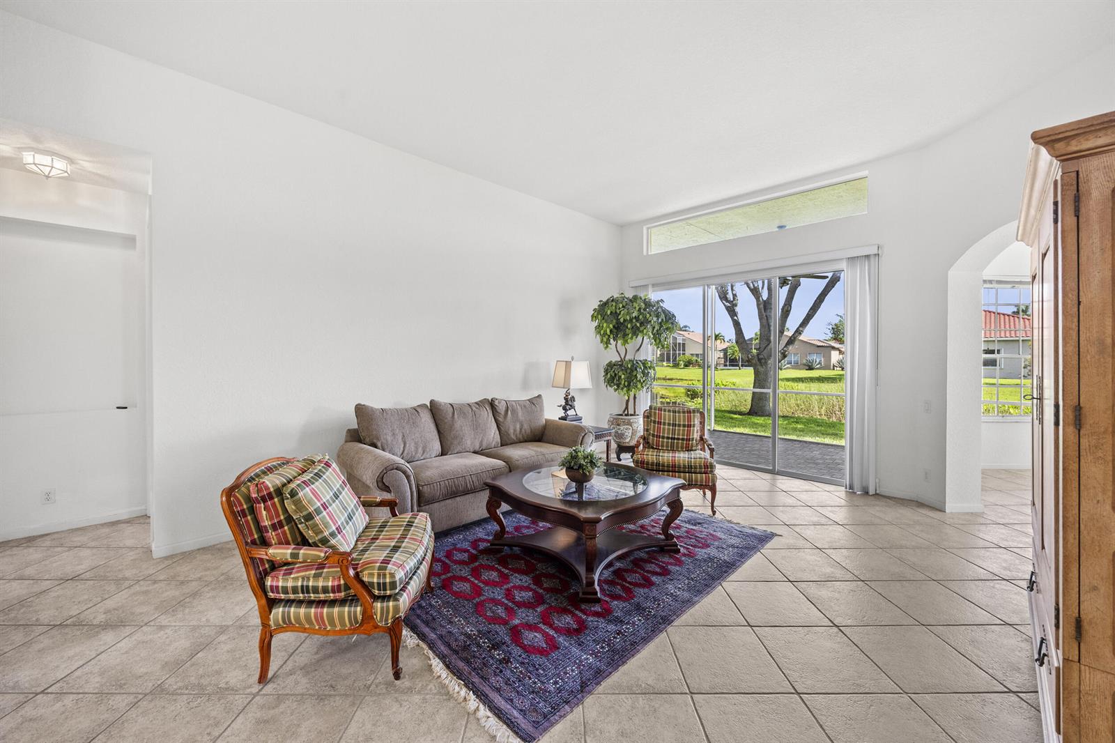 A living room with tile floors, a sofa, two plaid chairs, and a sliding glass door — 6721 Arno Way, Boynton Beach FL 33472, BOYNTON BEACH, FL