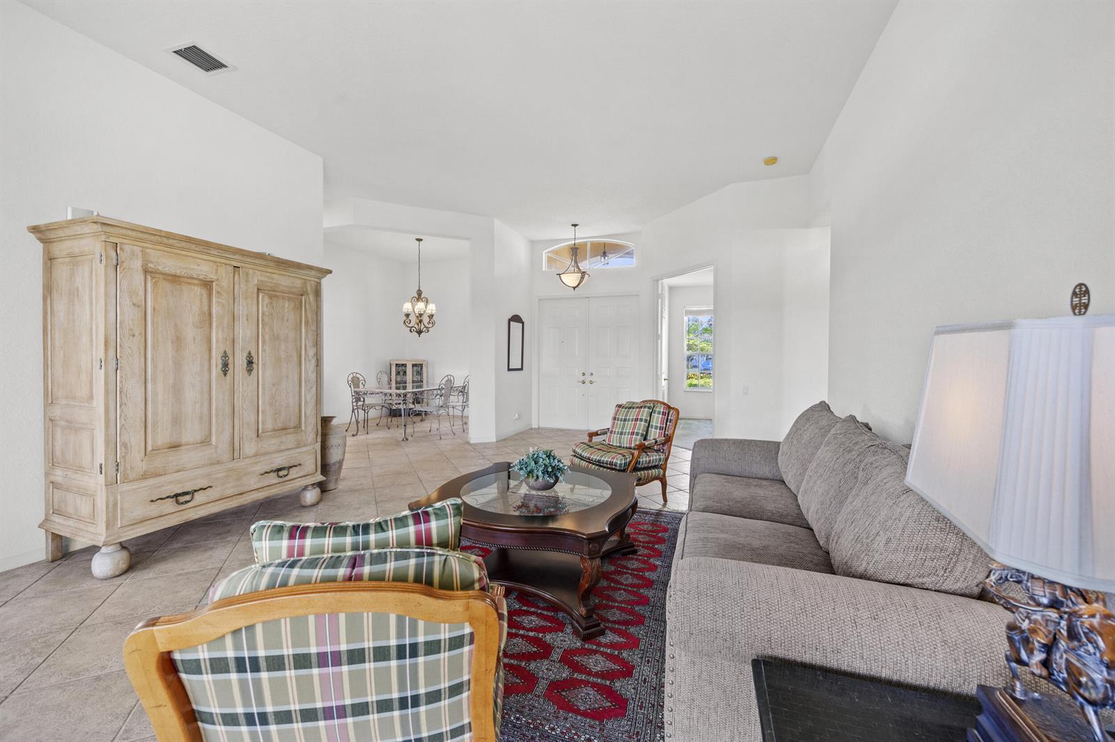 A living room features tile floors, a large wooden armoire, and a plaid armchair — 6721 Arno Way, Boynton Beach FL 33472, BOYNTON BEACH, FL