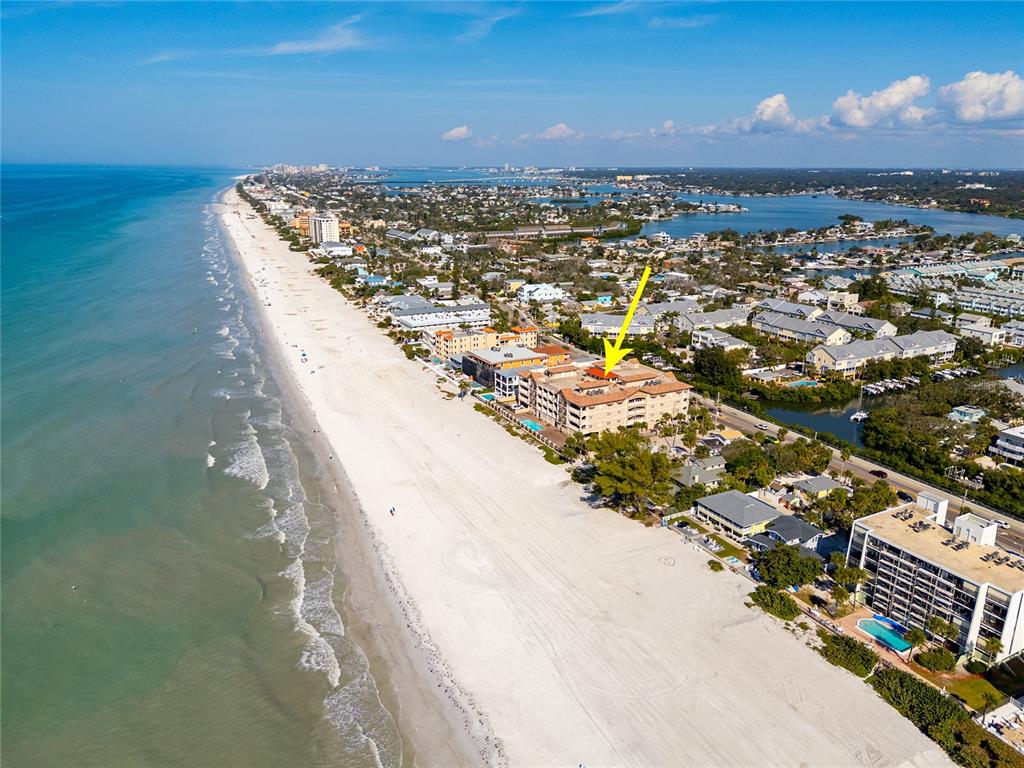 An aerial view shows a beachfront condominium complex with a yellow arrow pointing downward — 604 GULF BOULEVARD UNIT 207, INDIAN ROCKS BEACH, FL