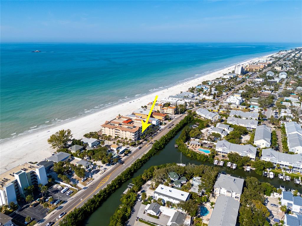 An aerial view shows a multi-story beachfront building marked by a yellow arrow — 604 GULF BOULEVARD UNIT 207, INDIAN ROCKS BEACH, FL