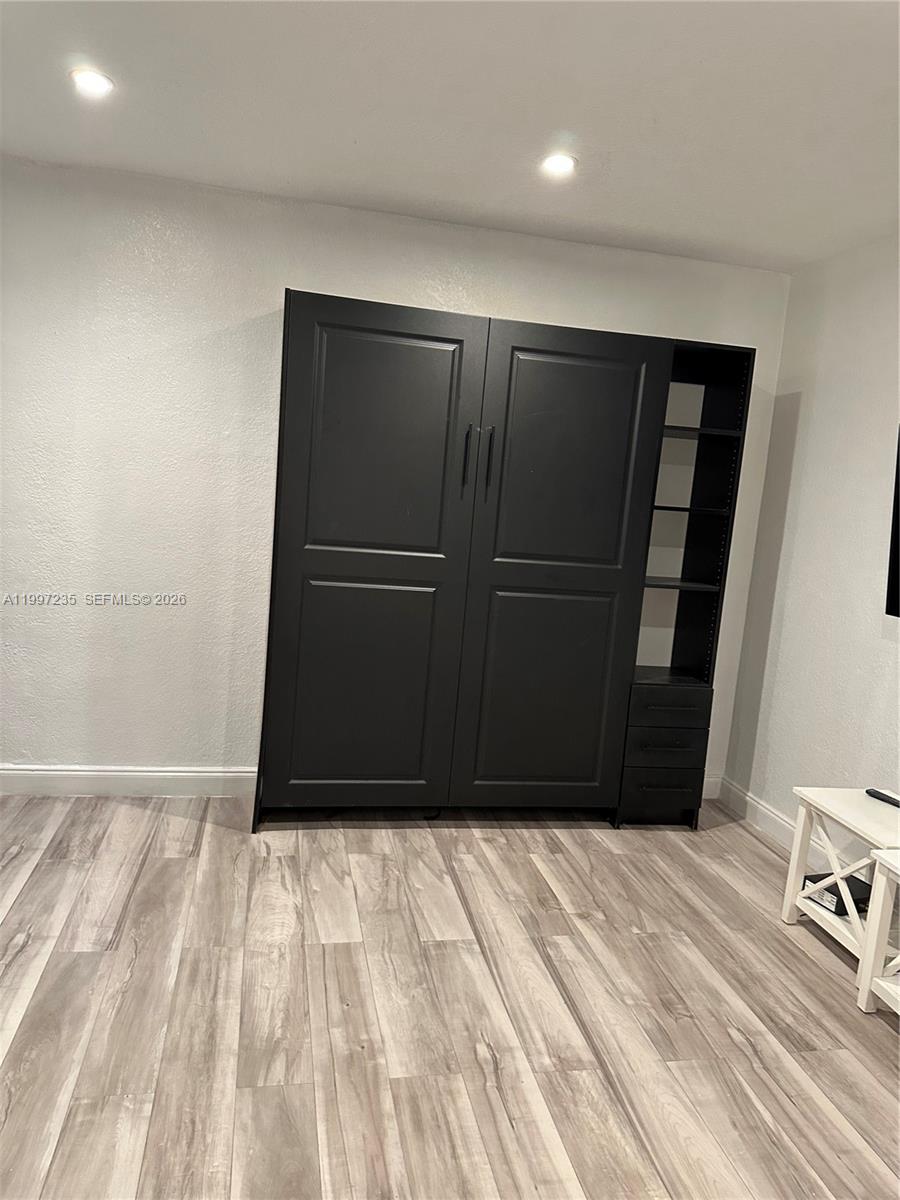 A room features a black Murphy bed unit with integrated shelving and light wood-look flooring — 8401 Crespi Blvd # 3, Miami Beach FL 33141, MIAMI BEACH, FL