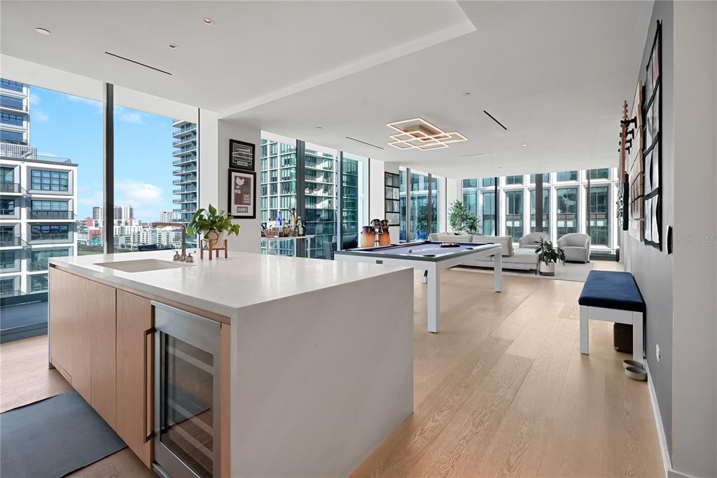 A modern open-concept living area features a kitchen island, pool table, and floor-to-ceiling windows — 1000 WATER STREET UNIT 1002, TAMPA, FL