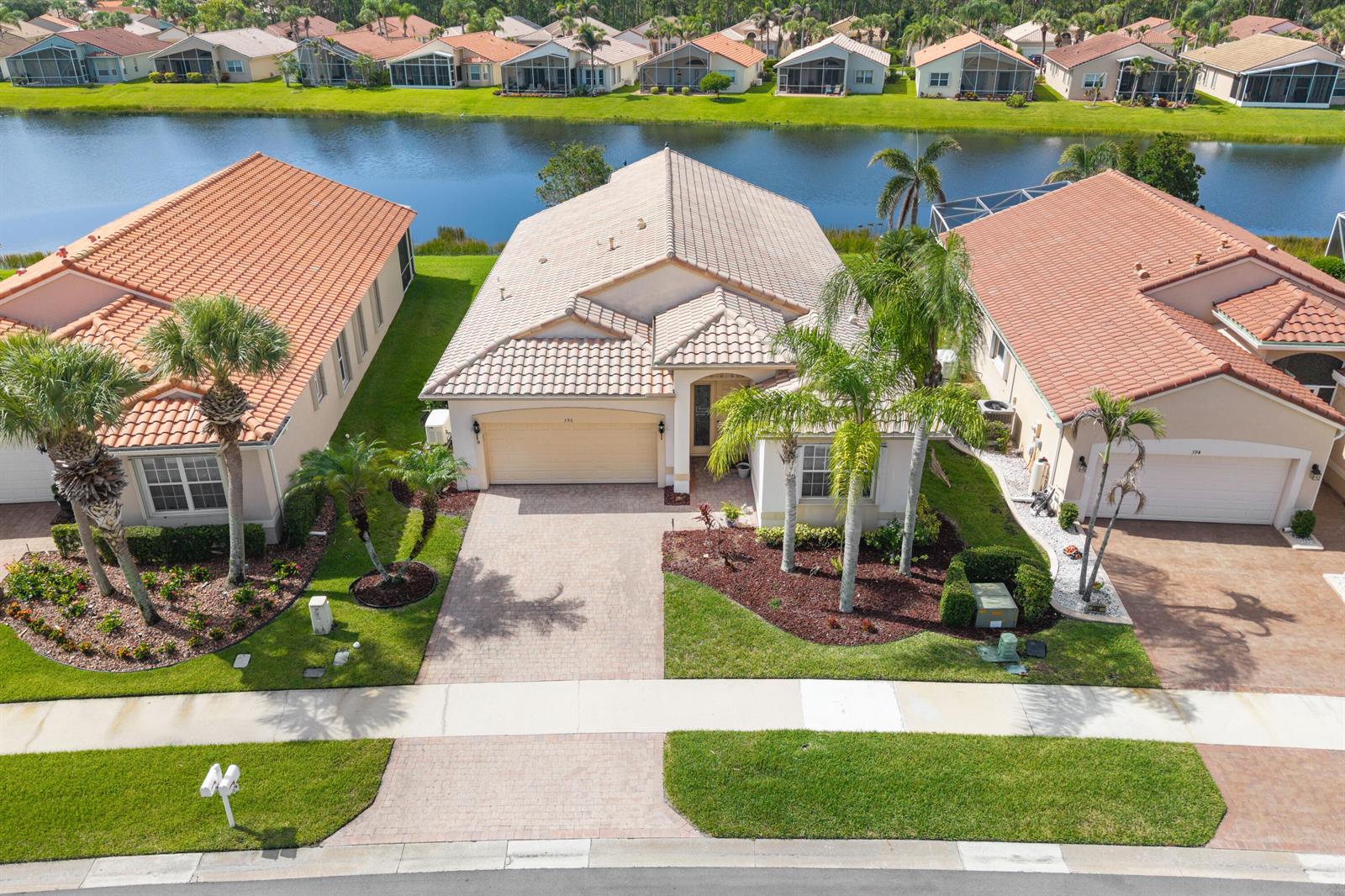 An aerial view shows a suburban house with a tiled roof and a waterfront backyard — 396 NW SPRINGVIEW Loop, Port St. Lucie FL 34986, PORT ST. LUCIE, FL