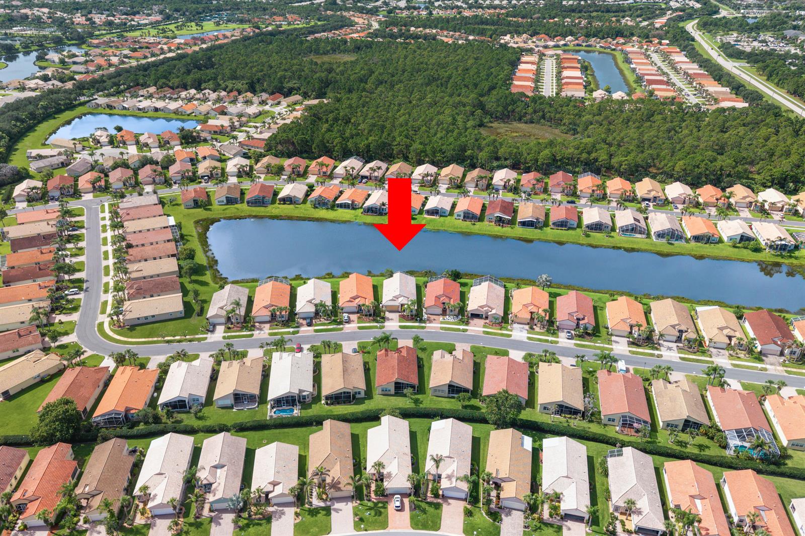 An aerial view shows a residential neighborhood with houses surrounding a central lake — 396 NW SPRINGVIEW Loop, Port St. Lucie FL 34986, PORT ST. LUCIE, FL