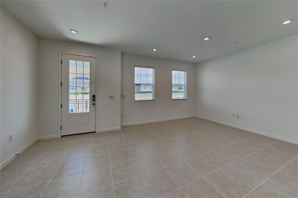 An empty room features light-colored tile flooring, white walls, recessed lighting, and a glass-paneled door — 4216 SADLER ROAD, APOPKA, FL