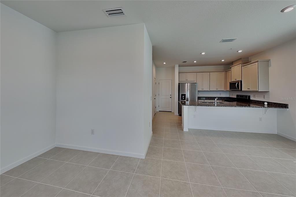 An open-concept kitchen features light-colored cabinetry, dark granite countertops, and tile flooring — 4216 SADLER ROAD, APOPKA, FL
