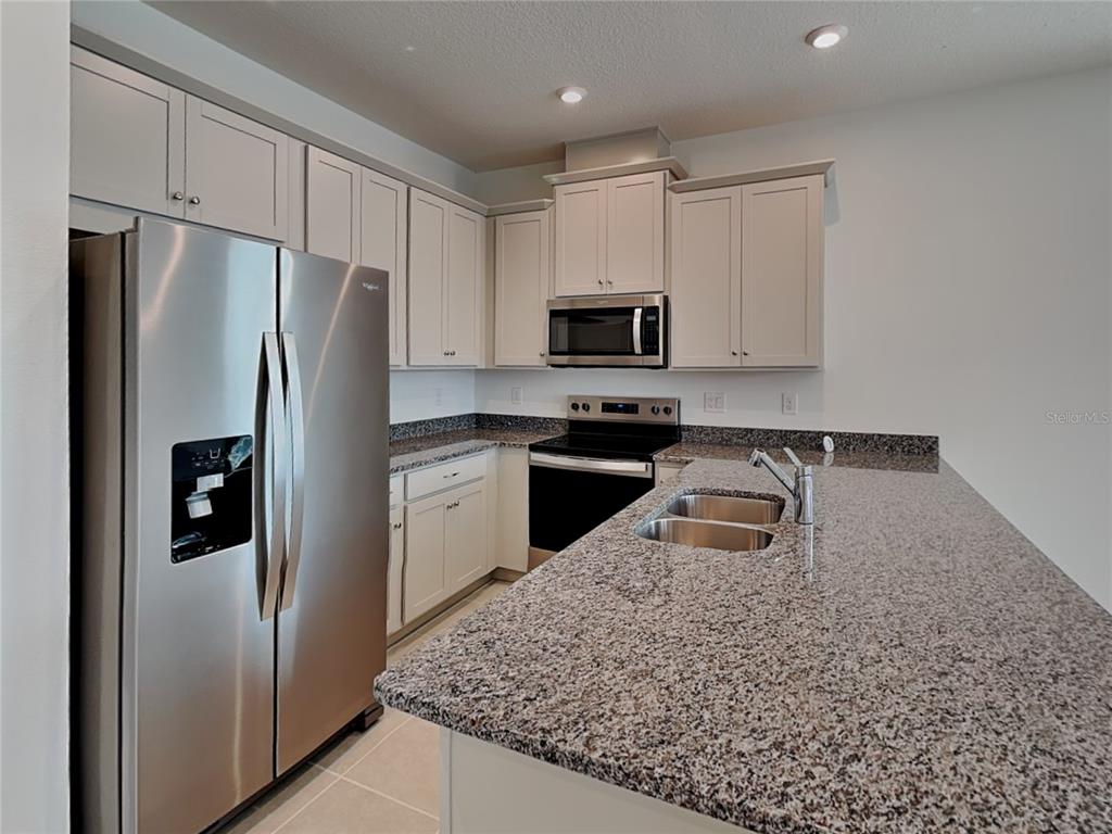A kitchen with light-colored cabinets, granite countertops, stainless steel appliances, and a central island — 4216 SADLER ROAD, APOPKA, FL